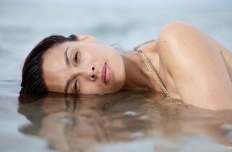 Asian chick Tera Patrick models in the ocean while wearing a gold bikini