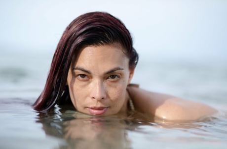 Asian chick Tera Patrick models in the ocean while wearing a gold bikini