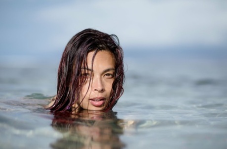 Asian chick Tera Patrick models in the ocean while wearing a gold bikini