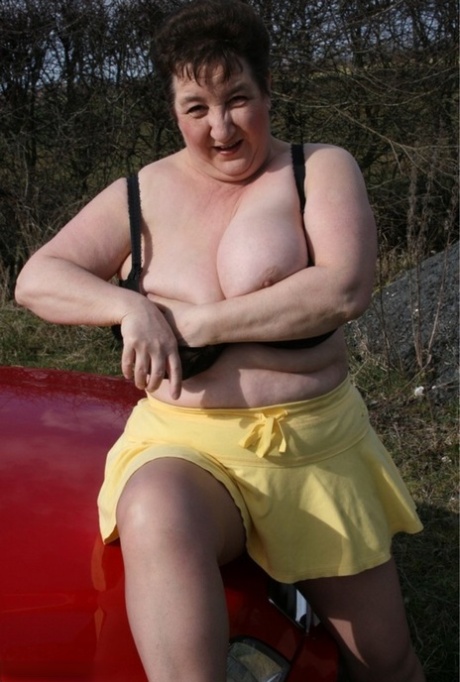 Mature fatty Kinky Carol gets naked over her car while in the outdoors